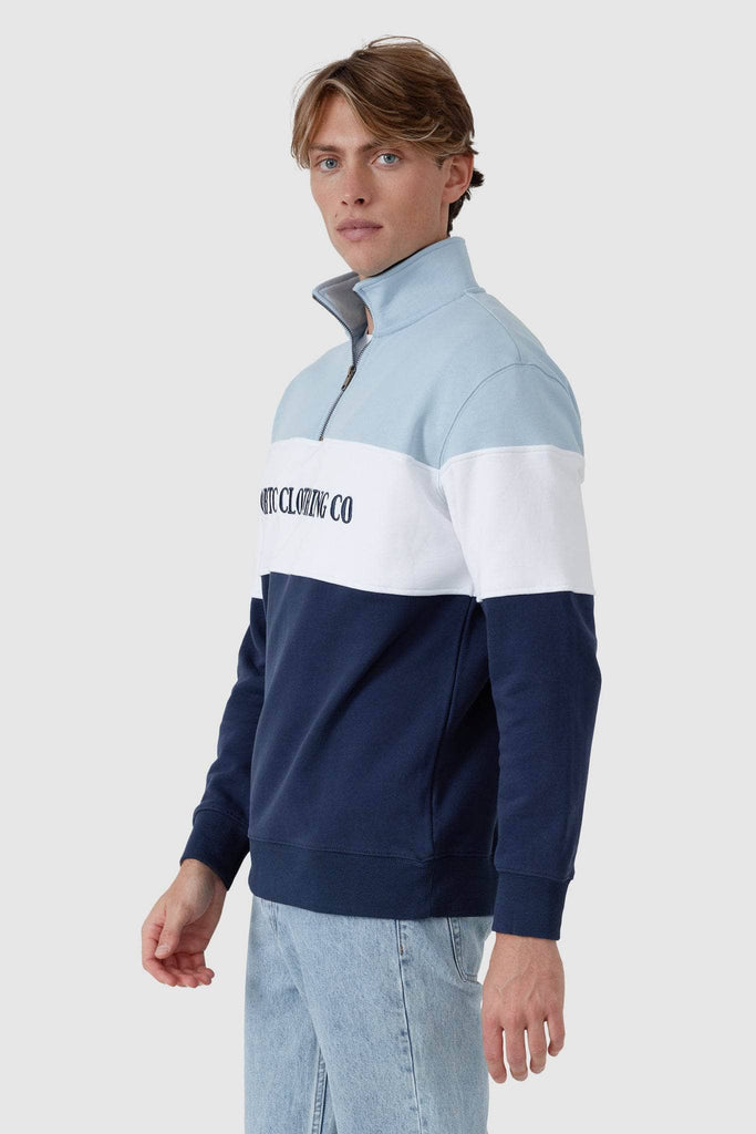 Male model wearing quarter zip jumper that has a light blue top panel, white middle panel with navy embroidered ortc Clothing Co and navy base panel