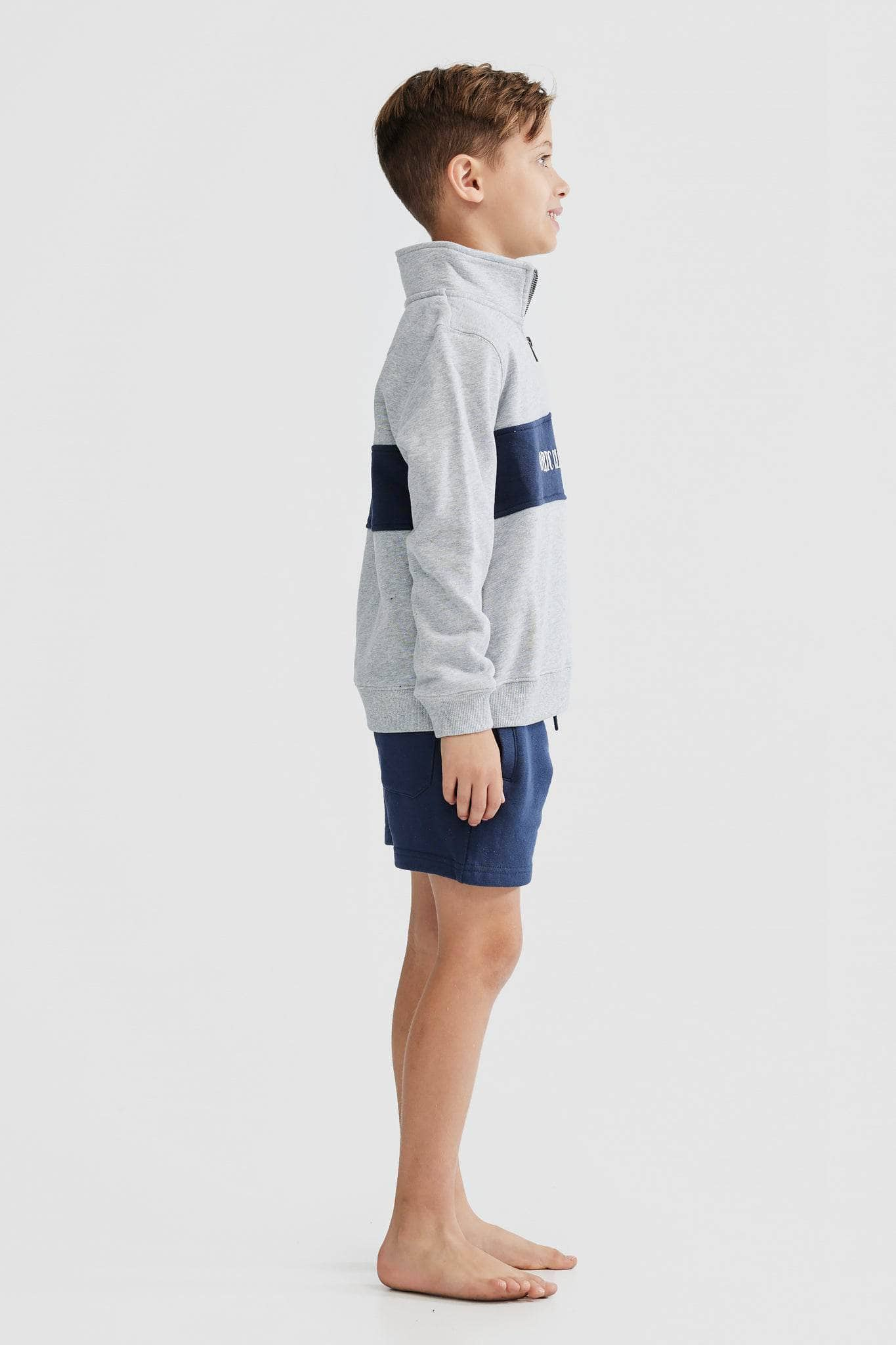 Child model wearing grey quarter zip with navy middle panel and white embroidered ortc clothing co